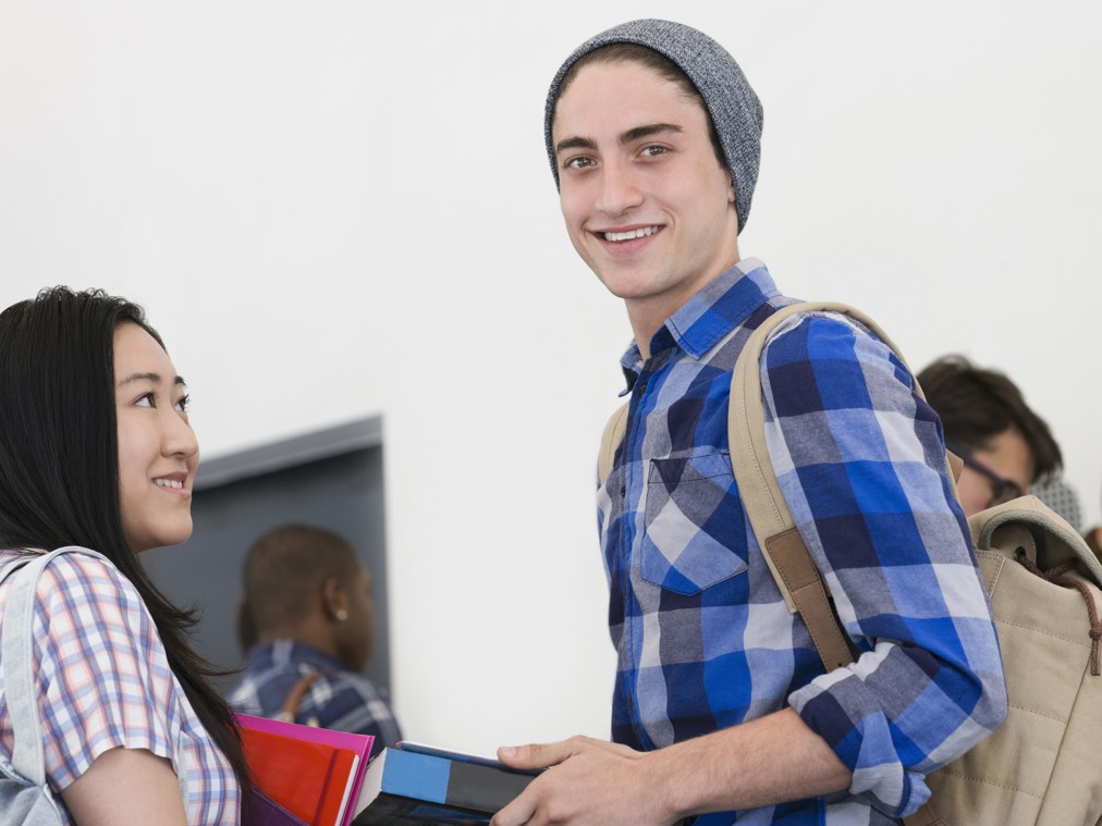 En unga man och en ung kvinna ler och håller i foldrar.