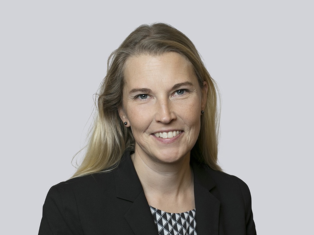 En kvinna i svart kavaj och mönstrad skjorta.