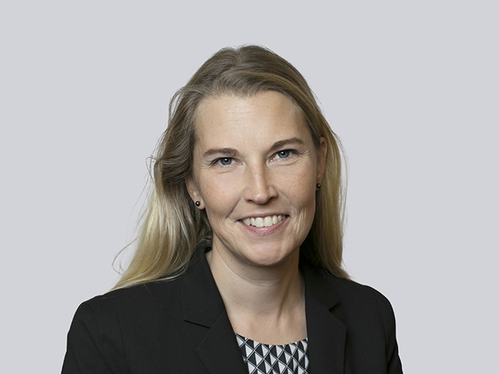 En kvinna i svart kavaj och mönstrad skjorta.