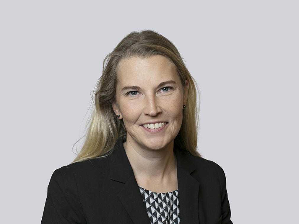 En kvinna i svart kavaj och mönstrad skjorta.