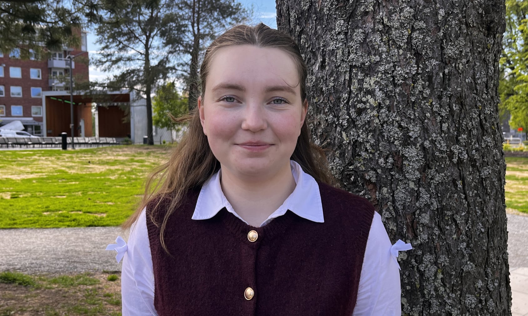 En kvinna som står bredvid ett träd i en park.