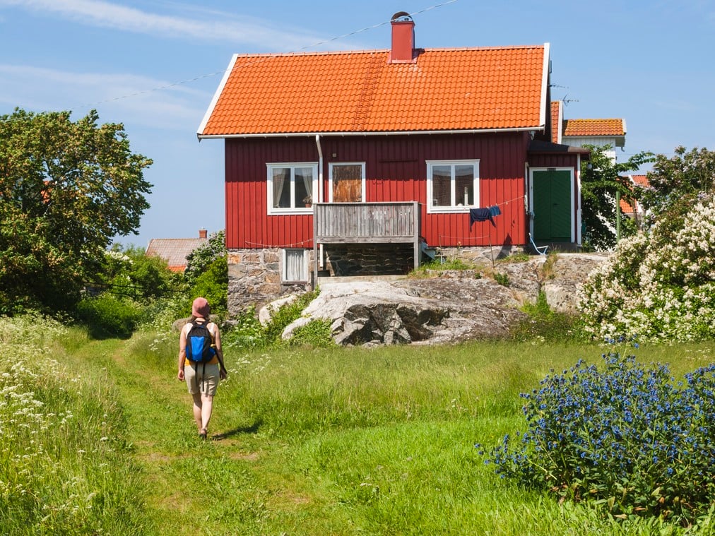 En person som går längs en stig framför ett rött hus.