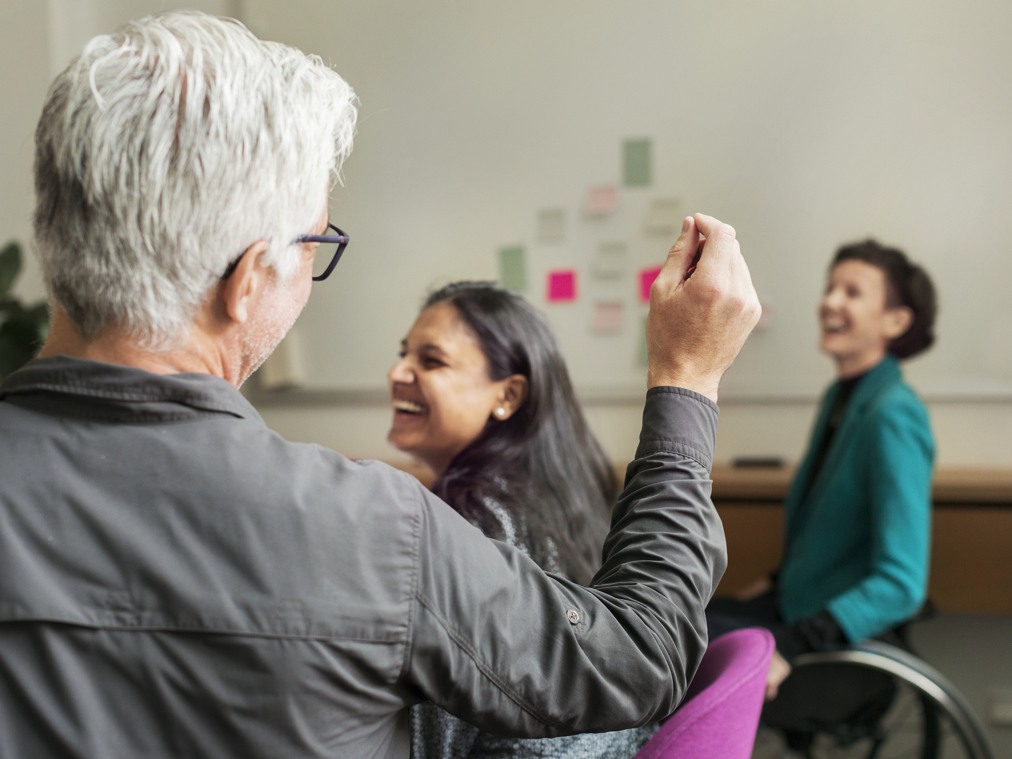 En man och två kvinnor sitter i ett rum och skrattar.