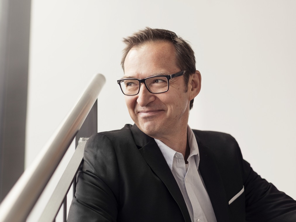 Leende person i mörk kostym.