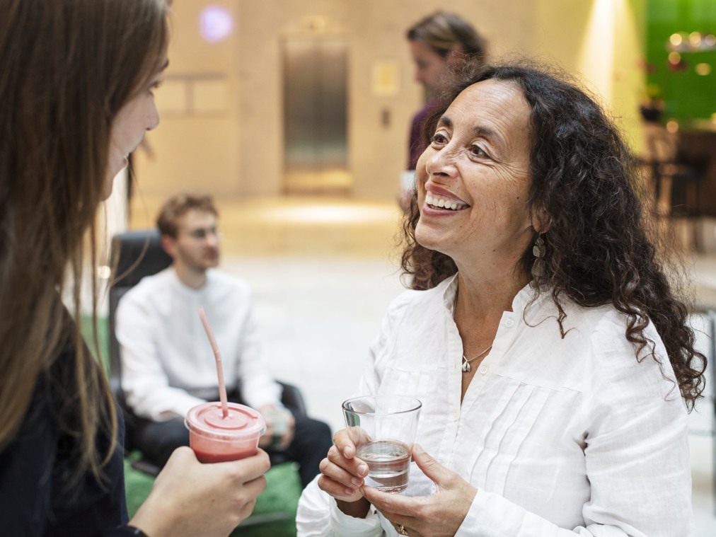 En kvinna pratar med en annan kvinna som håller i en smoothie.