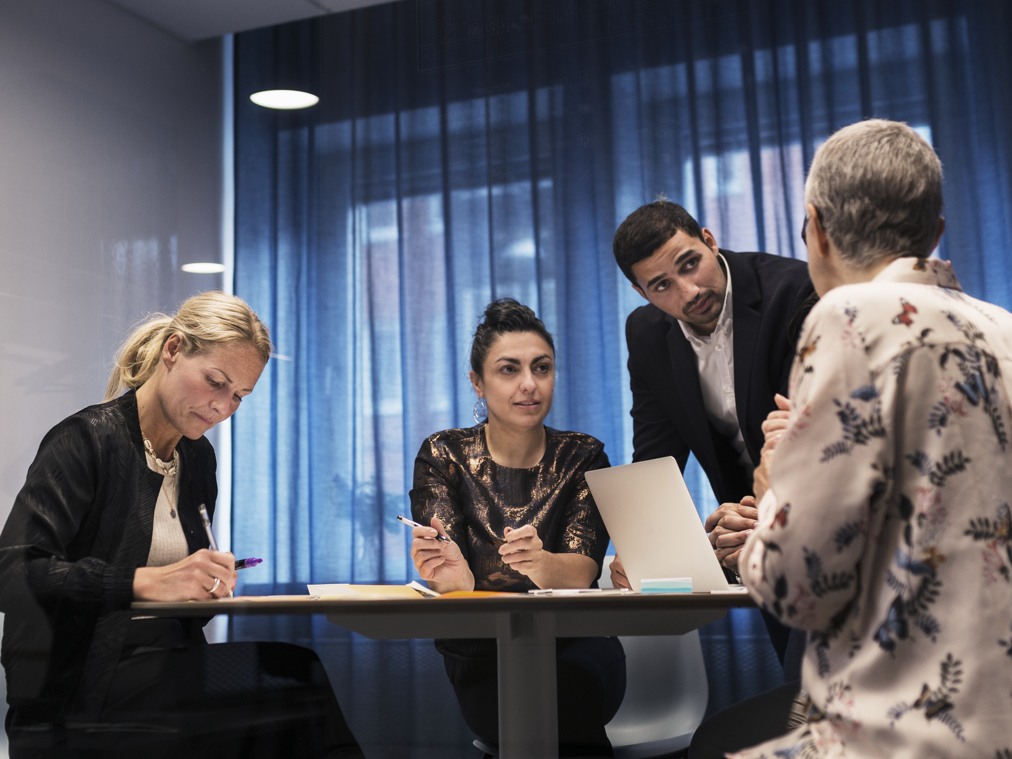 Arbetskamrater runt ett mötesbord.
