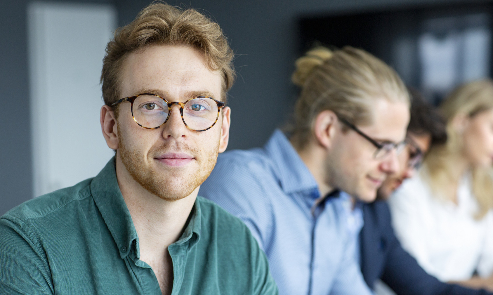 En grupp människor som sitter vid ett bord med bärbara datorer.
