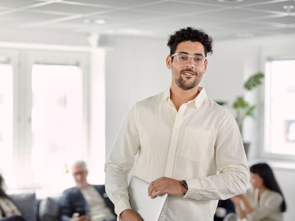 A man in a white shirt is holding a laptop.