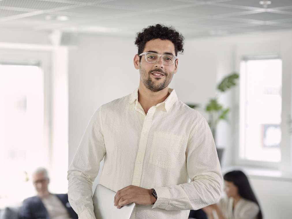 En man i vit skjorta i en kontorsmiljö.
