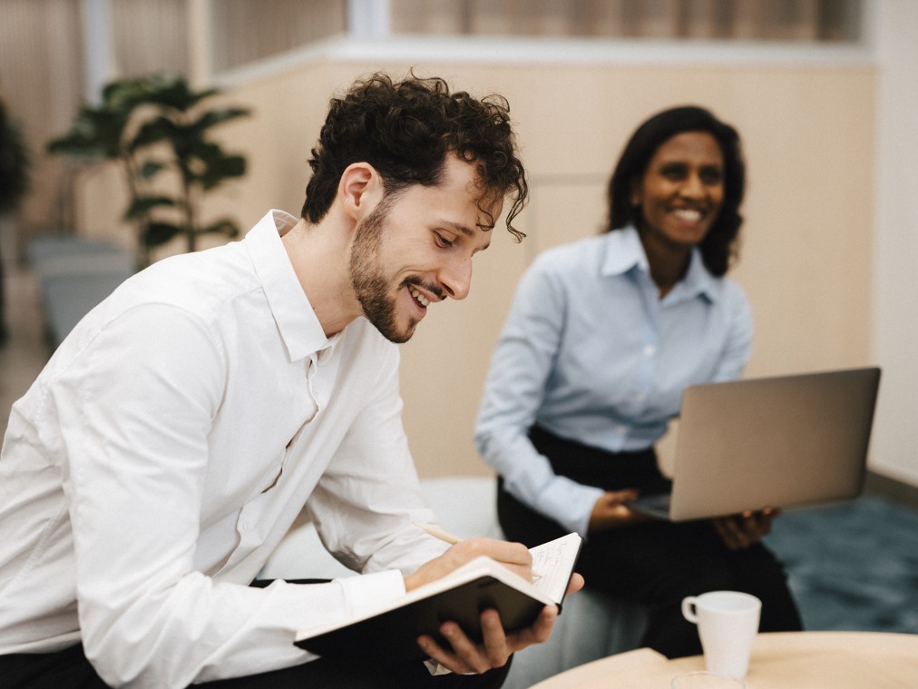 En man och en kvinna sitter i en soffa framför en bärbar dator.