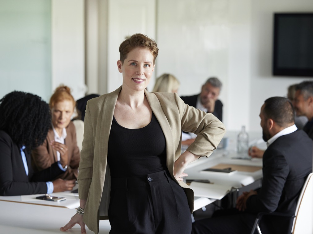 En kvinna som står framför en grupp människor i ett mötesrum.