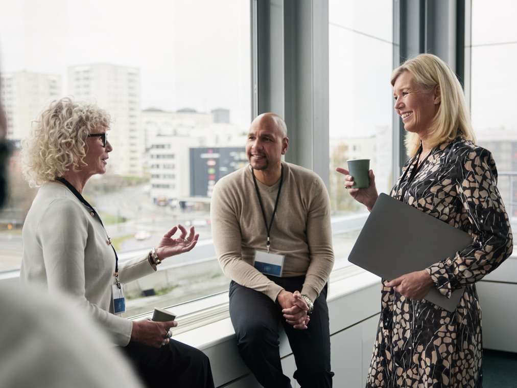 En grupp människor som står vid ett fönster i konferensrum.