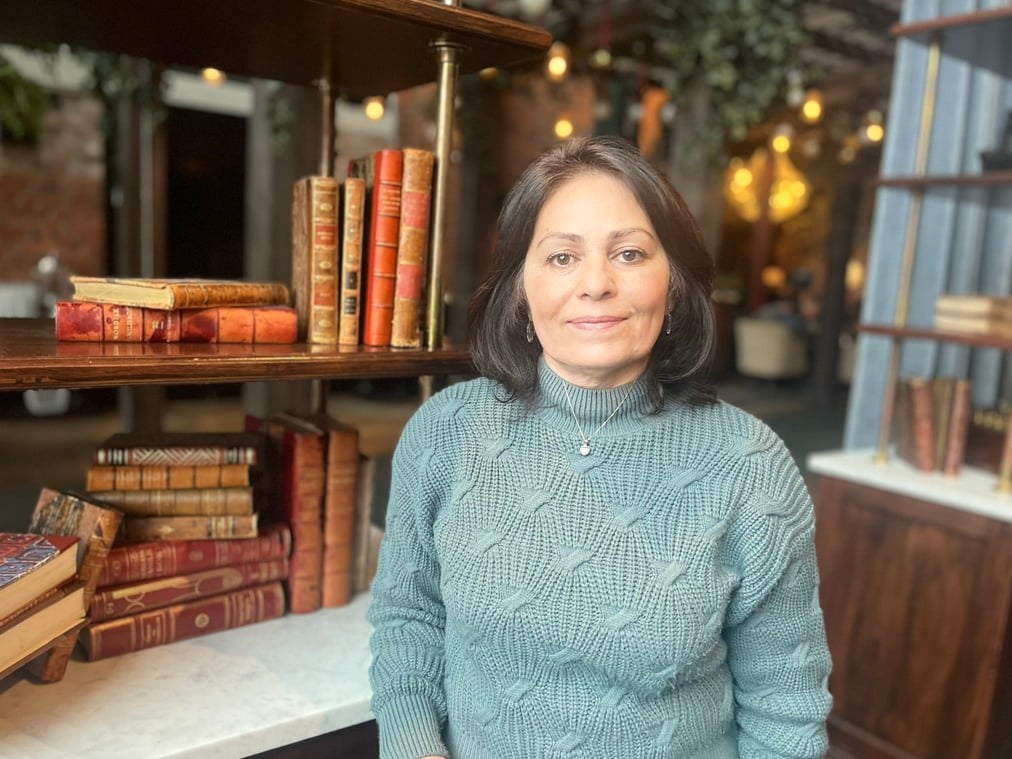 En person står framför en hylla med böcker.