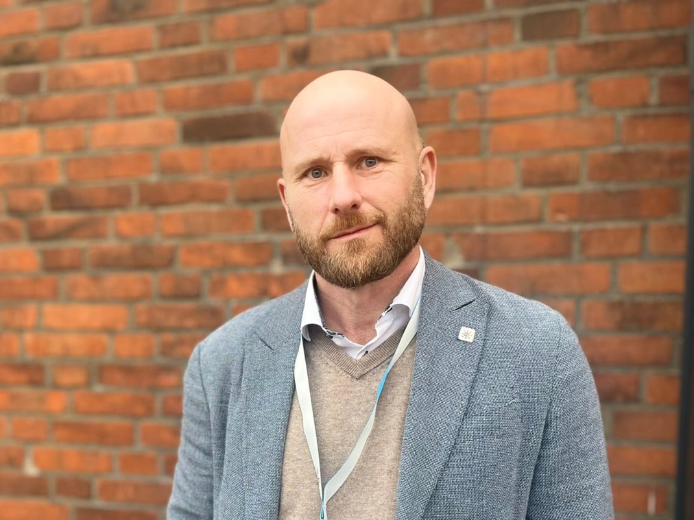 En man som står framför en tegelvägg.