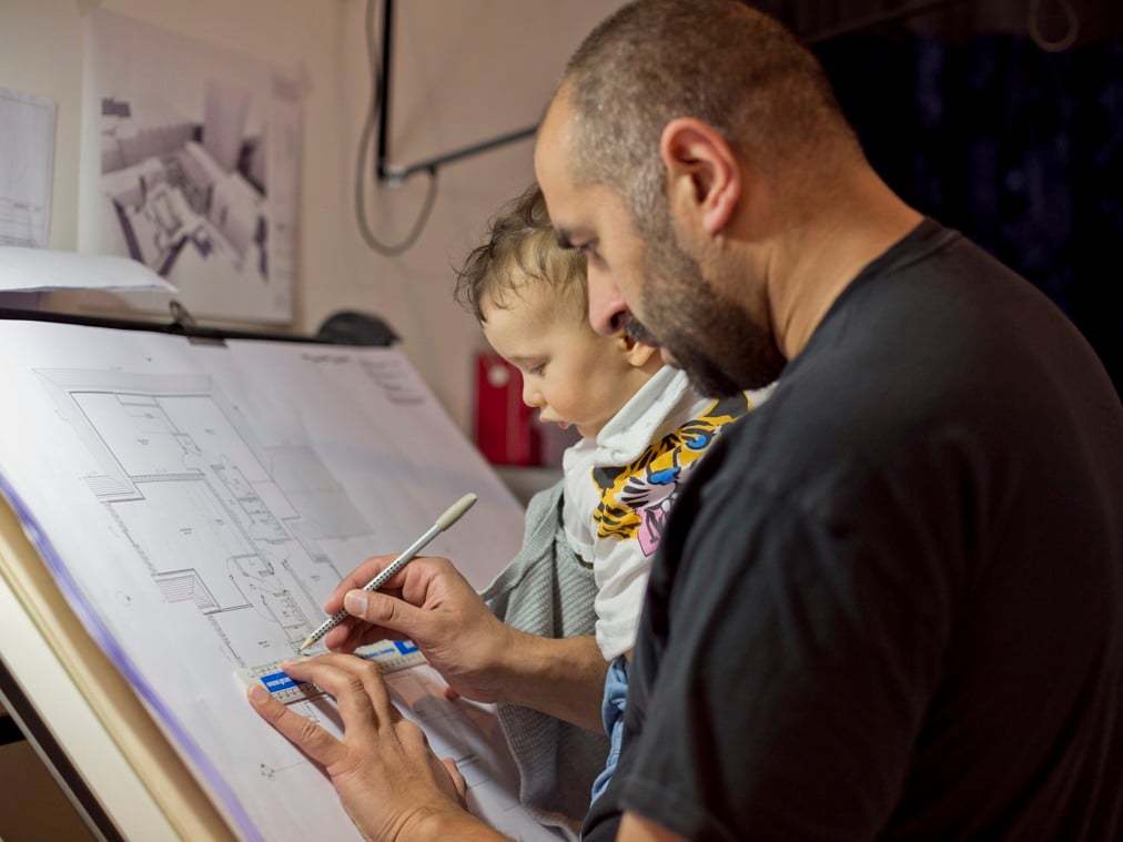 En man och ett barn tittar på en arkitektritning.